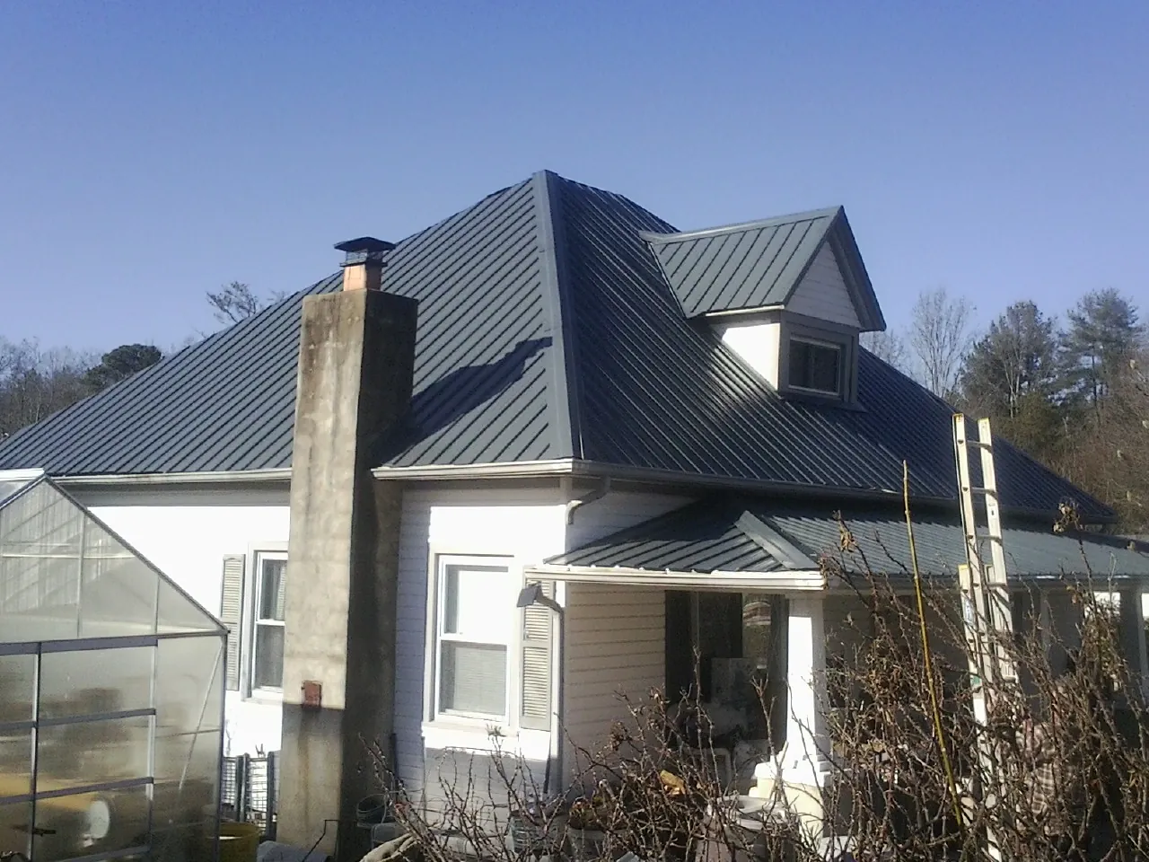 Dark blue standing seam metal roof on a white farmhouse with dormer — Slate & Tile Roof Repair by Roofing Brothers in Santa Monica