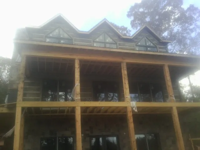 Dormers and porch framing on a large log home under construction — Roof Coating work by our crew in Santa Monica