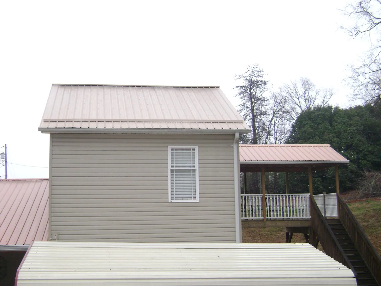 Tan metal roofs on a two story addition and attached porch, from a Roof Replacement job in Santa Monica