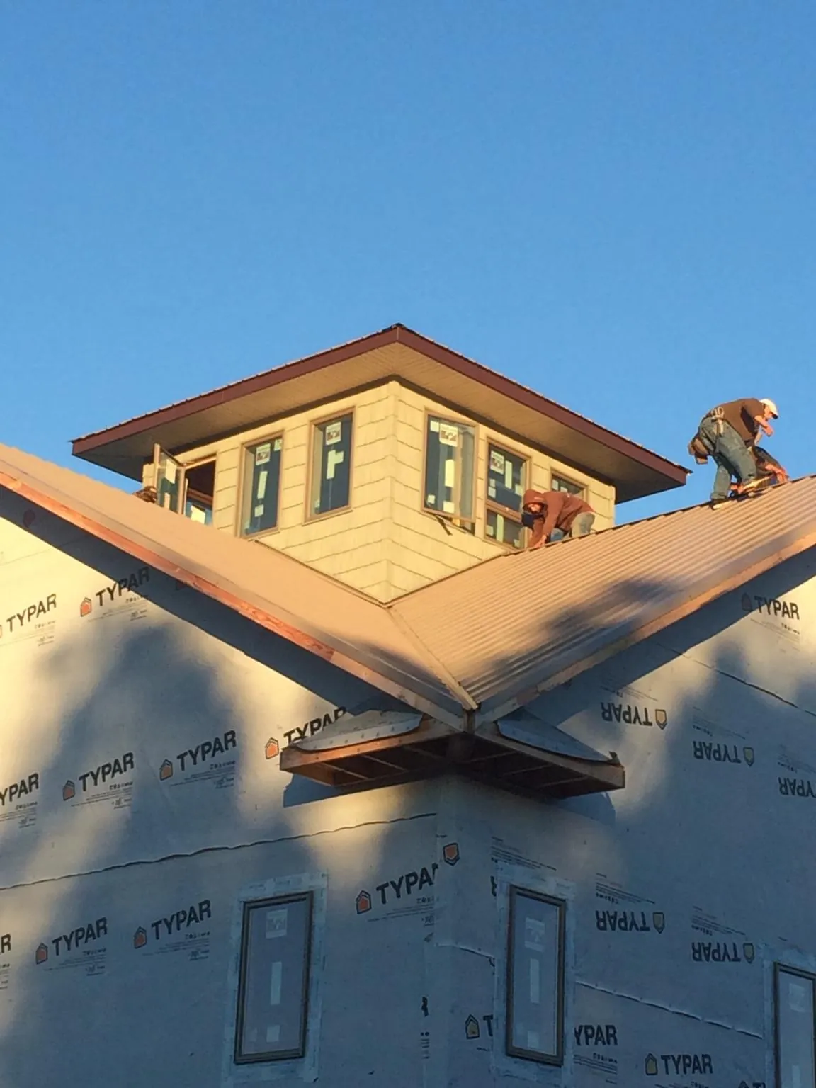 Roofers working around a rooftop cupola on a new metal roof at sunset — Roof Waterproofing in Santa Monica by Roofing Brothers